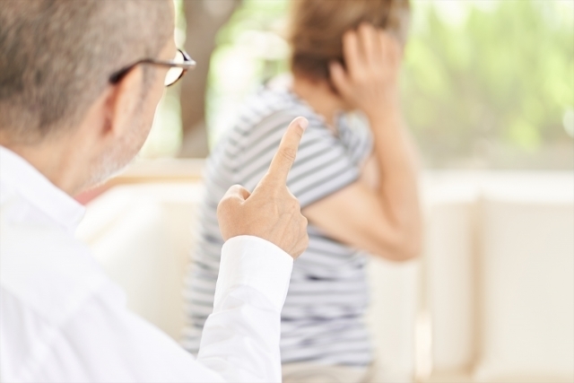 指を立ててきつく注意する男性と耳をふさいで顔をそむける女性