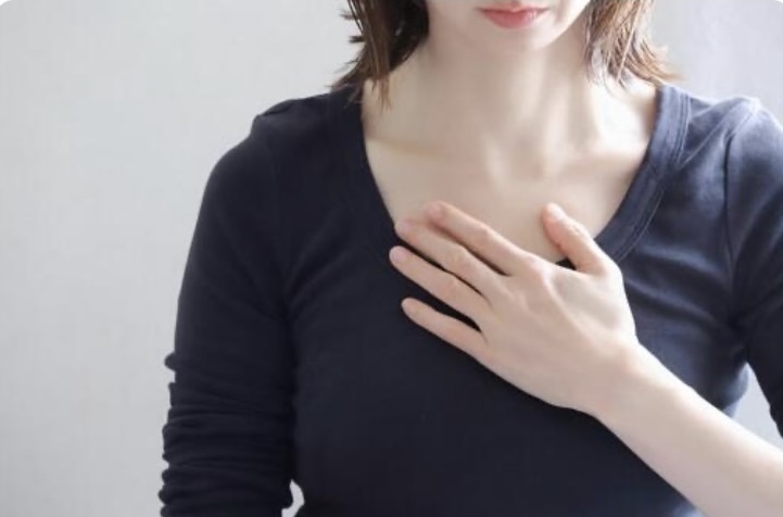 息苦しそうに胸に手を当てる女性