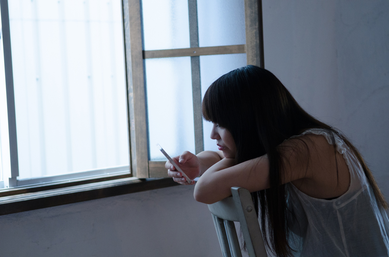 イスに座ってスマートフォンを操作する女性