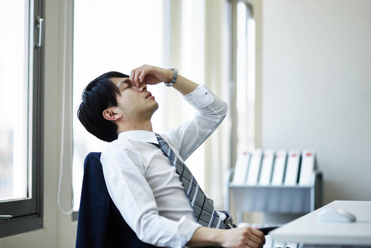 目頭を押さえ疲れた様子の男性