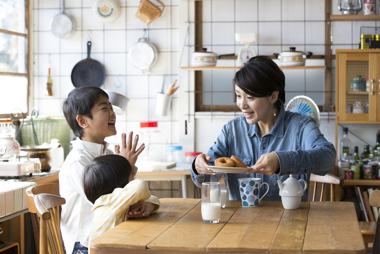 キッチンのテーブルでドーナツを食べる親子
