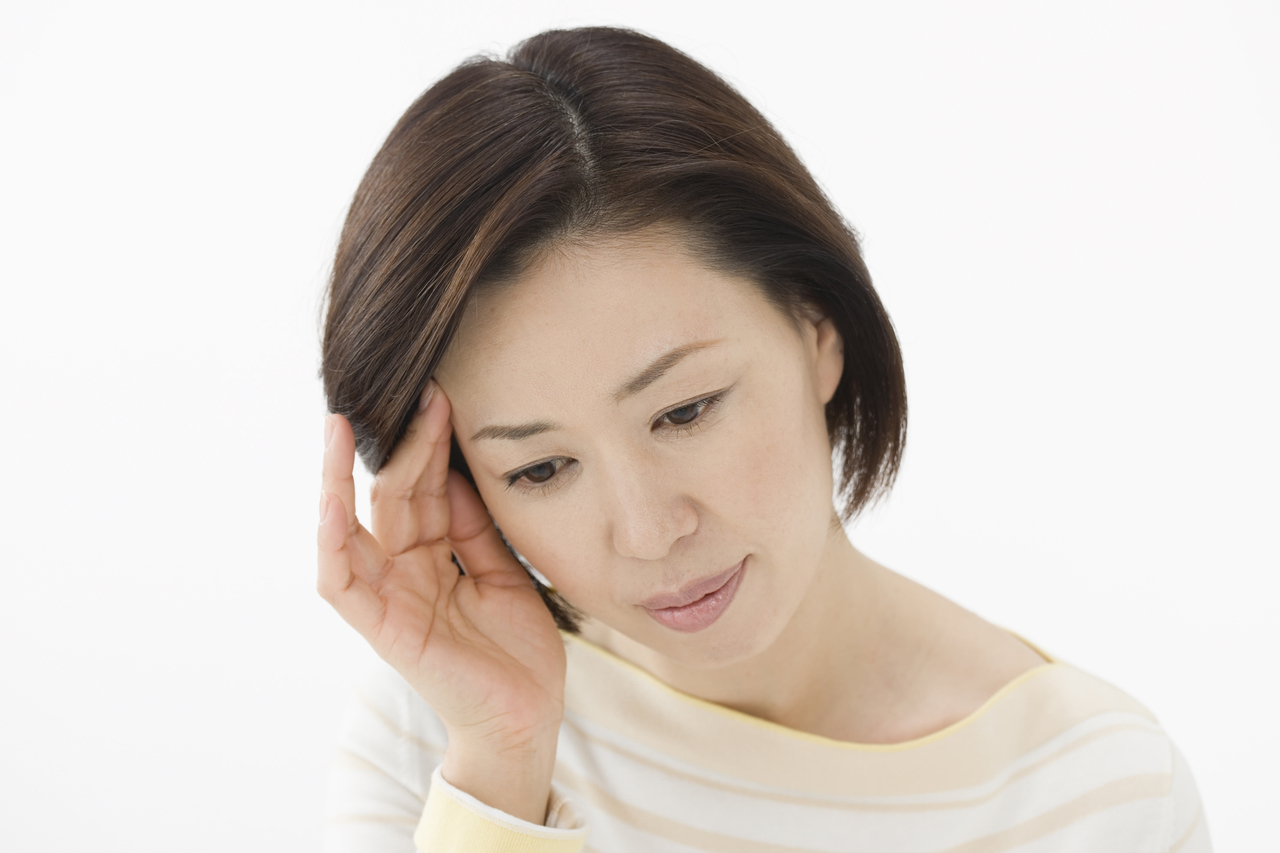 こめかみに指をあてる女性
