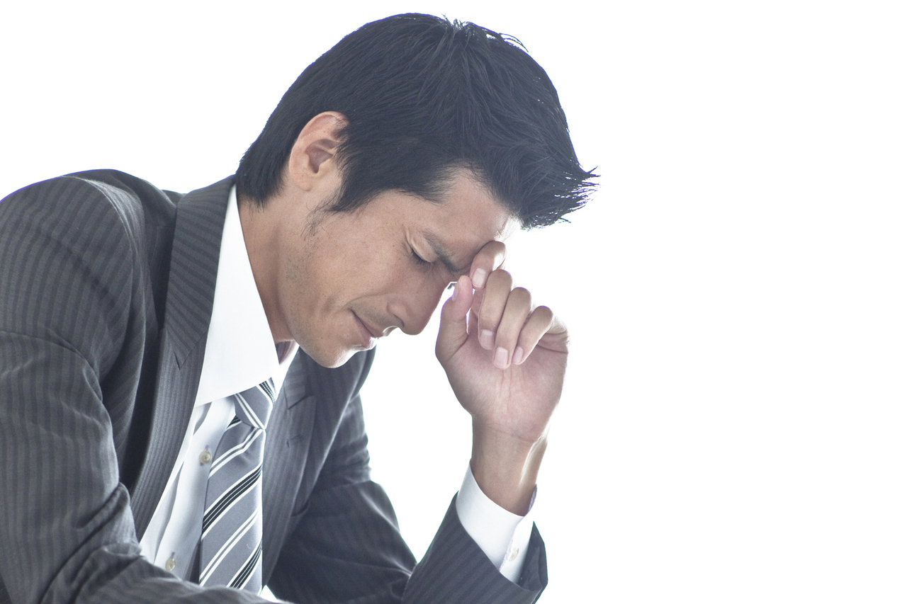 額に指をあてて考え込む男性