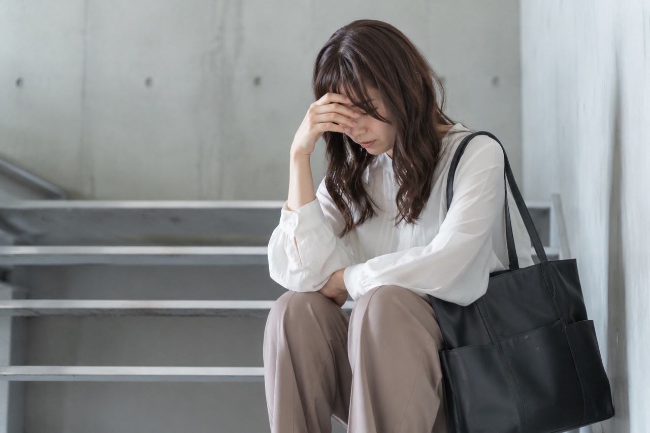 頭痛で座り込む女性