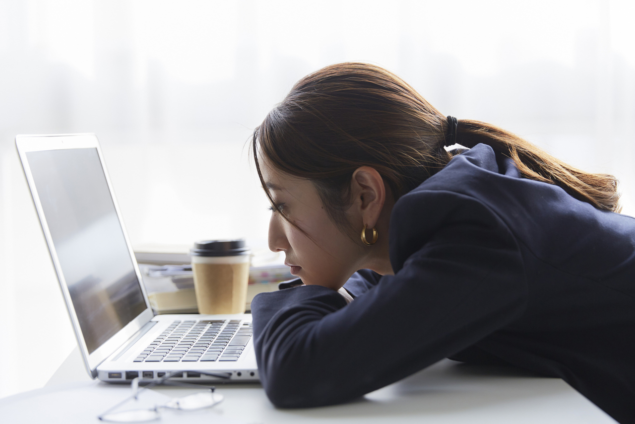 職場のデスクでパソコンを見て暗い表情の女性