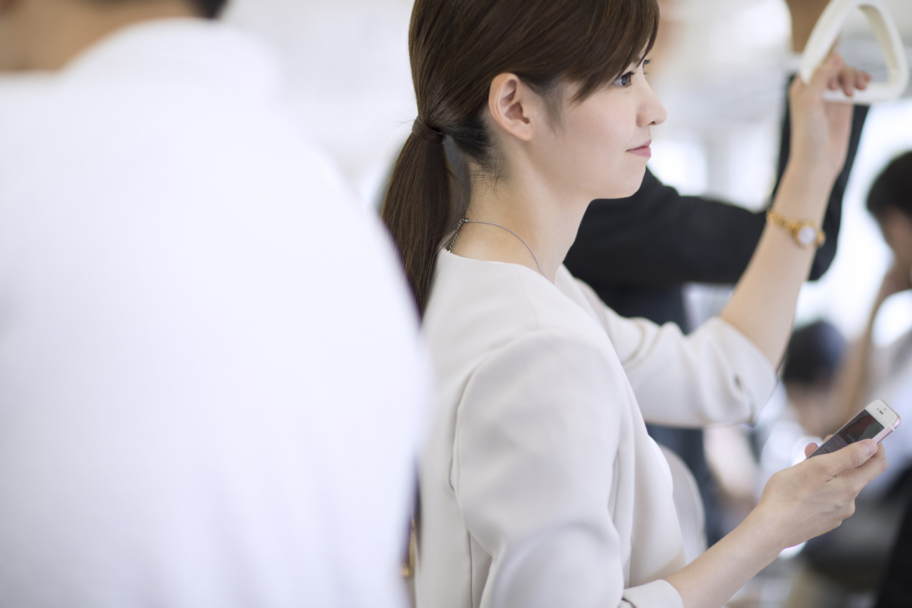 電車で外の景色を見つめ微笑む女性