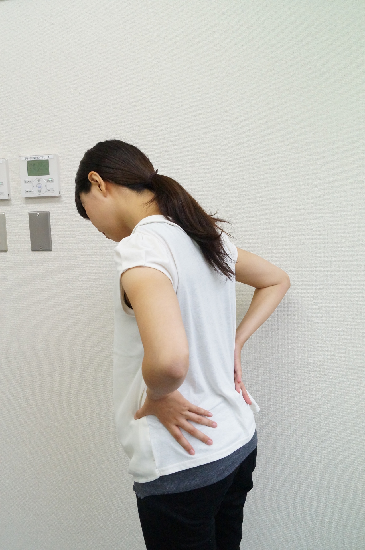 腰痛で腰をおさえる女性