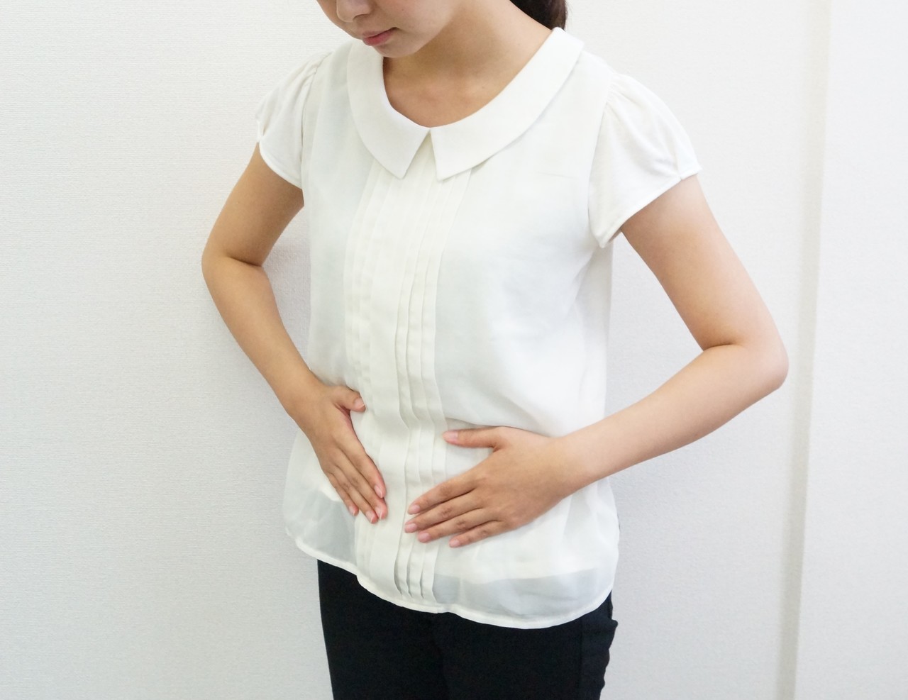 腹部をおさえる女性