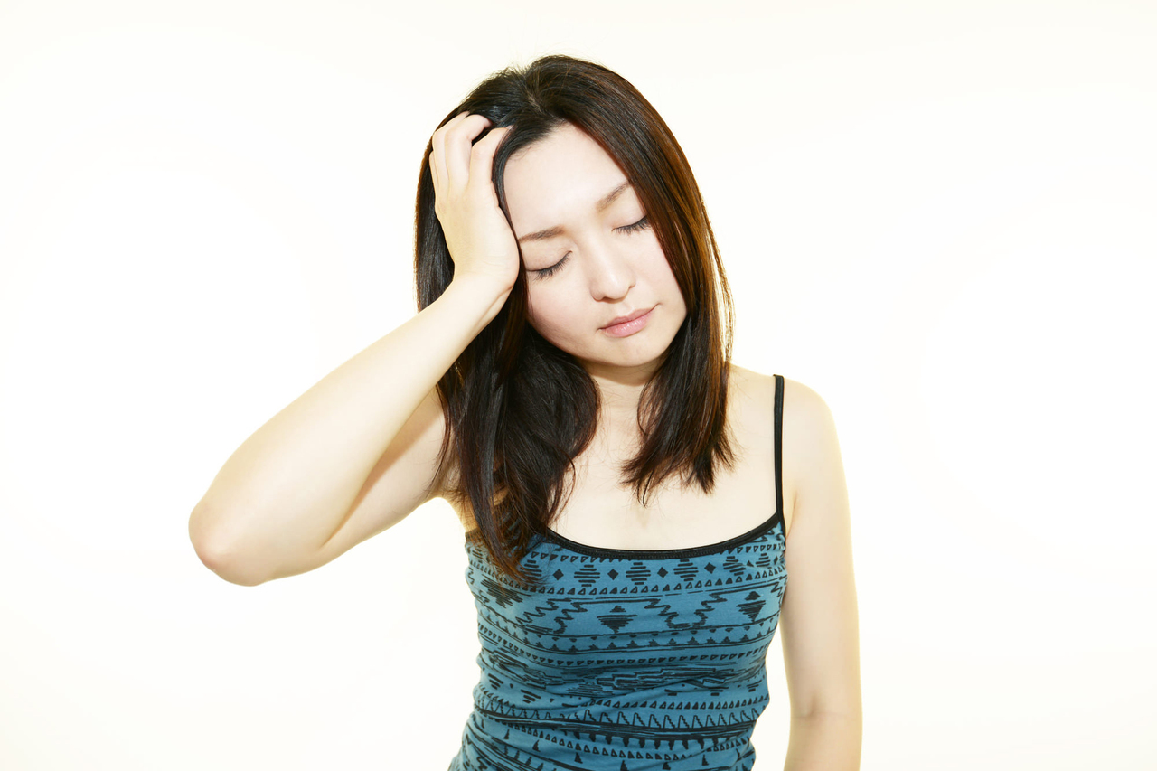 頭痛で額に手をあてる女性