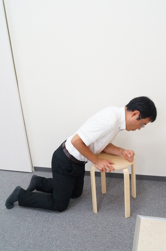 腰痛で椅子に倒れ掛かる男性