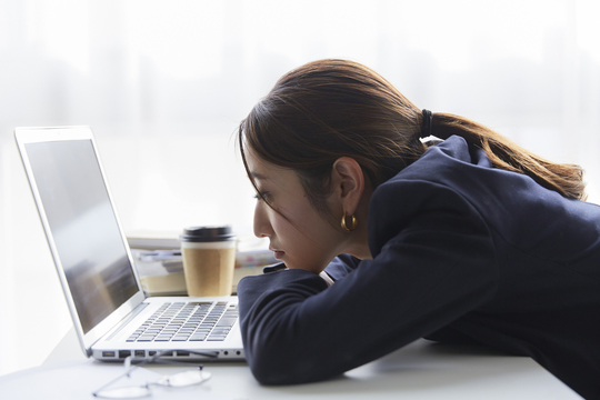 職場のデスクでパソコンを見て暗い表情の女性